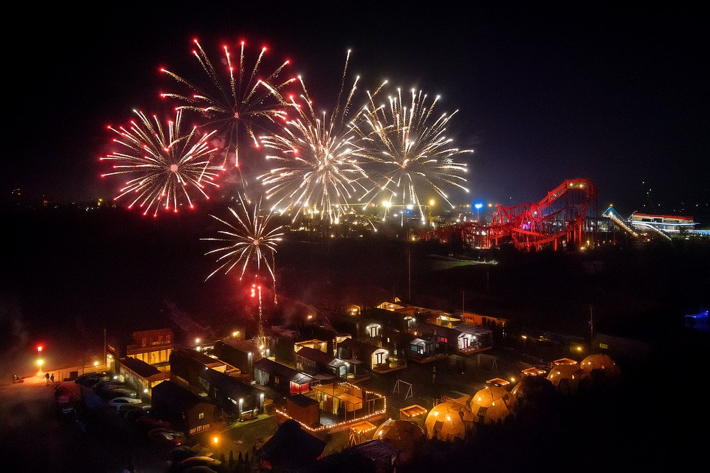 Panorama parku rozrywki z fajerwerkami w sylwestrową noc.